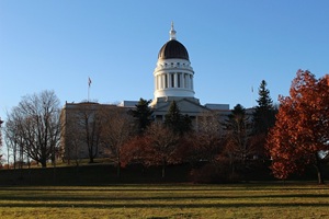 the Maine capitol building in Augusta stands behind a row of trees